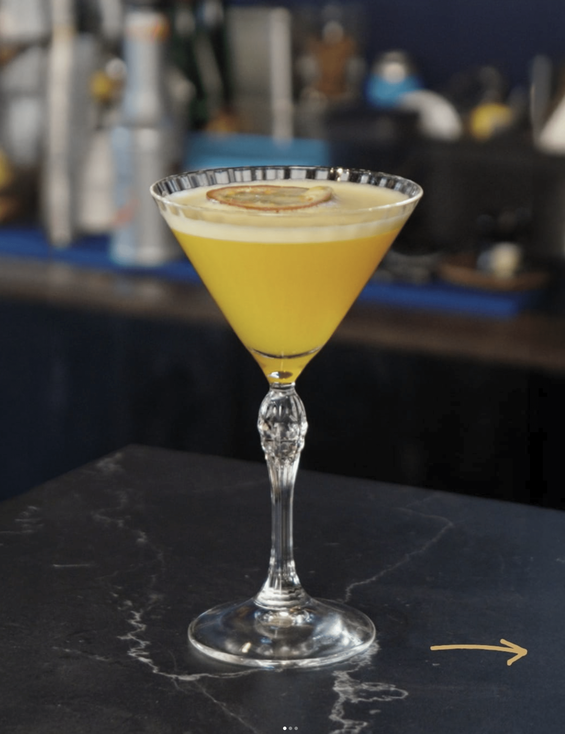 Gele cocktail in cocktailglas met gedroogde citrusschijf op de bar van Condao