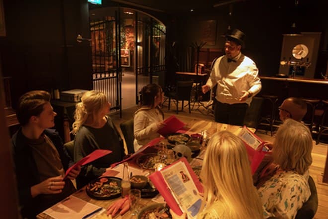 Gezelschap speelt het Moordspel aan tafel tijdens een groepsuitje